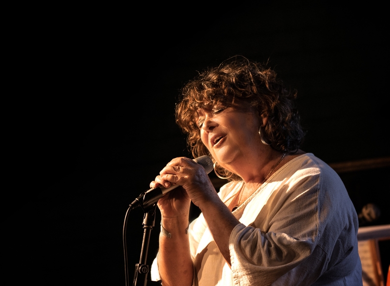 Colour photo of Tina singing at a microphone